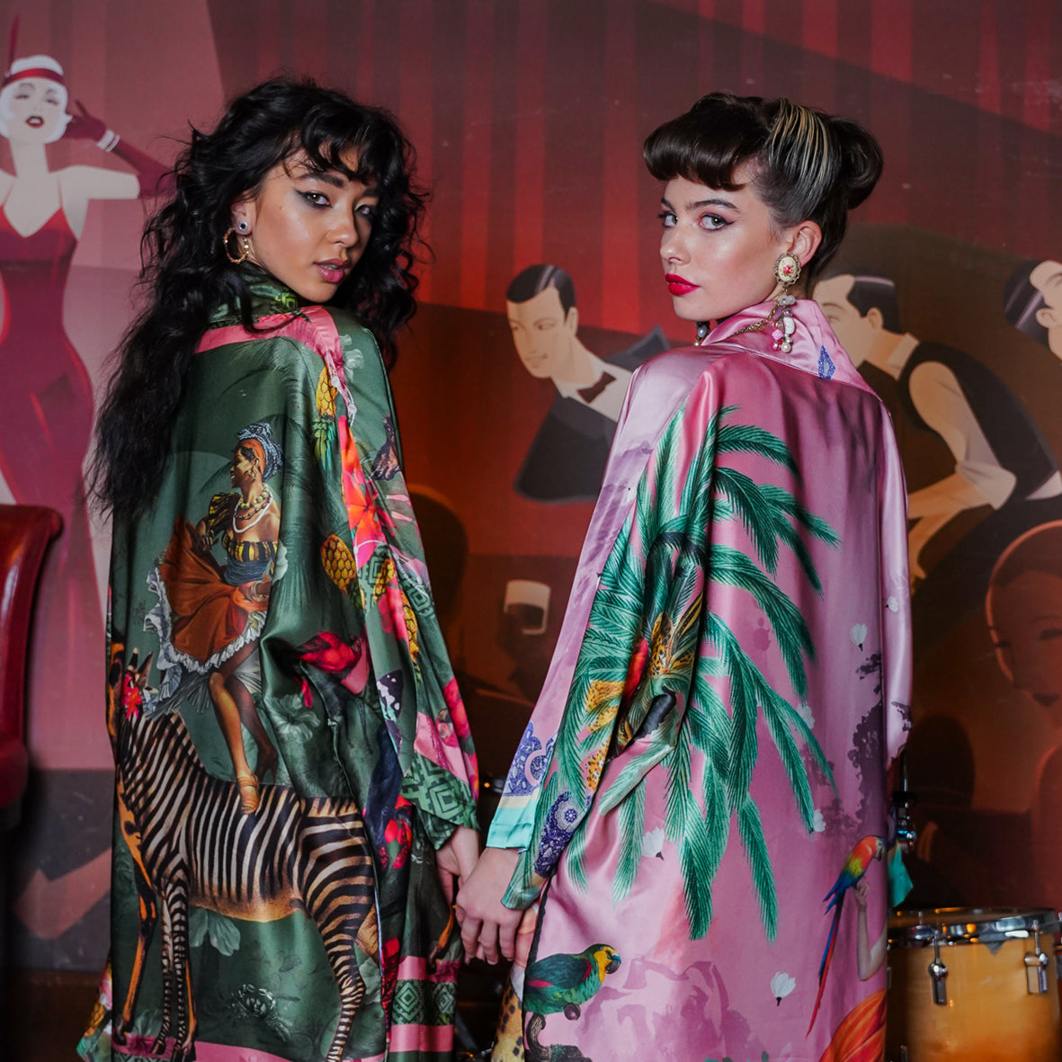 A female model showing a back view of luxury 100% silk Kimono in a maximalist Carnival inspired design against an olive background