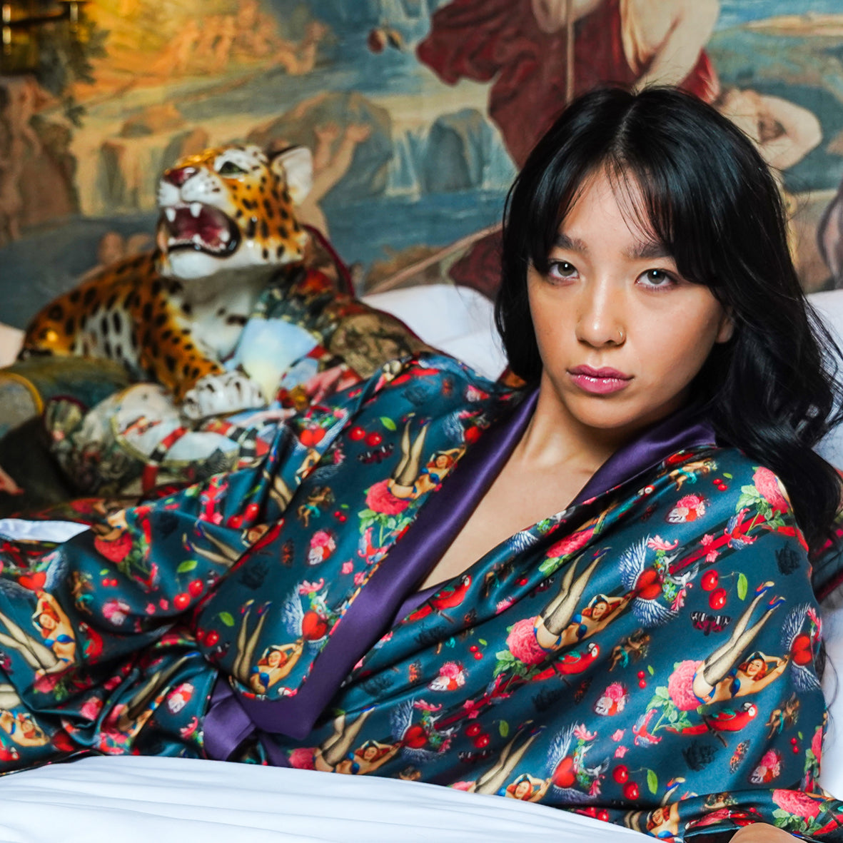 Female model lying down wearing luxury 100% silk kimono in a maximalist retro pinup design with cherries