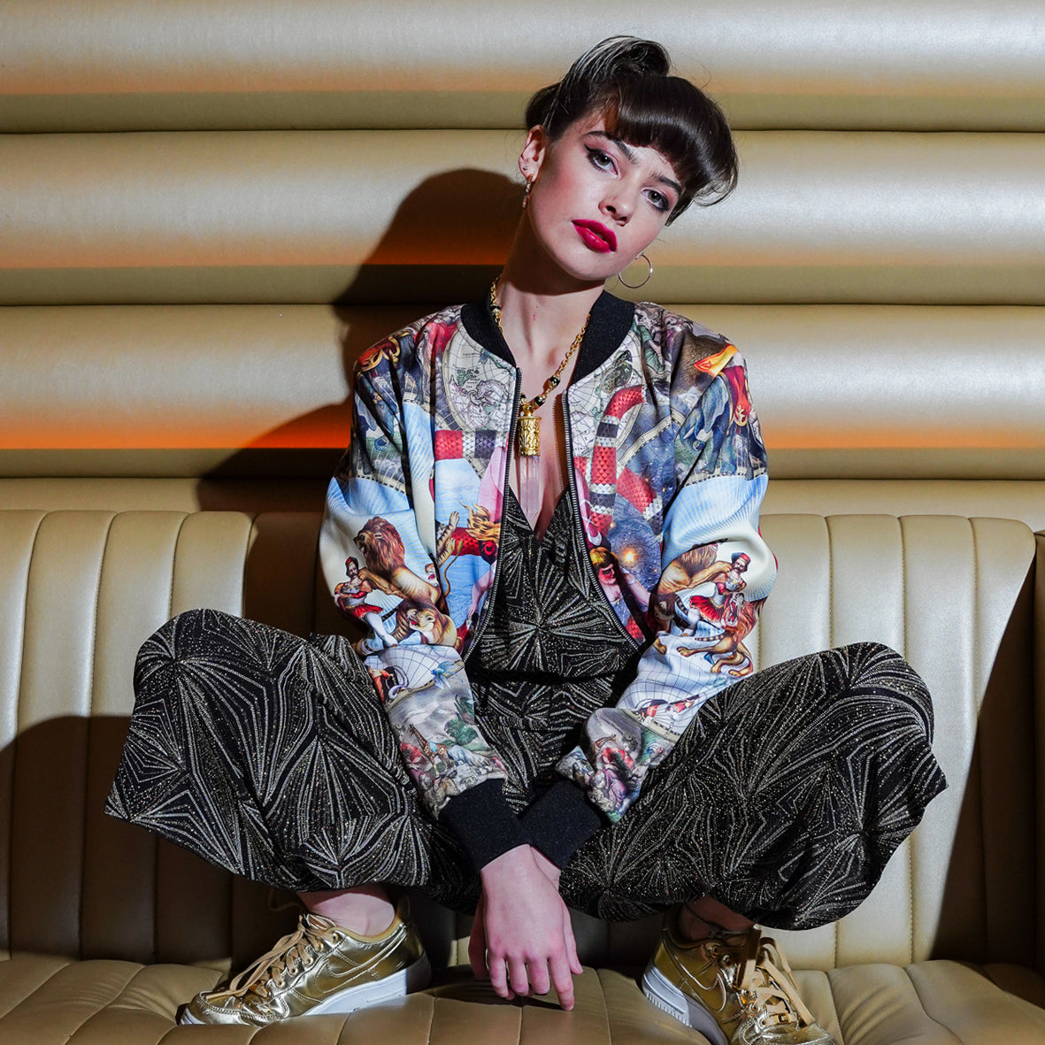 Female model on sofa wearing luxury softshell bomber jacket in a maximalist Circus inspired design