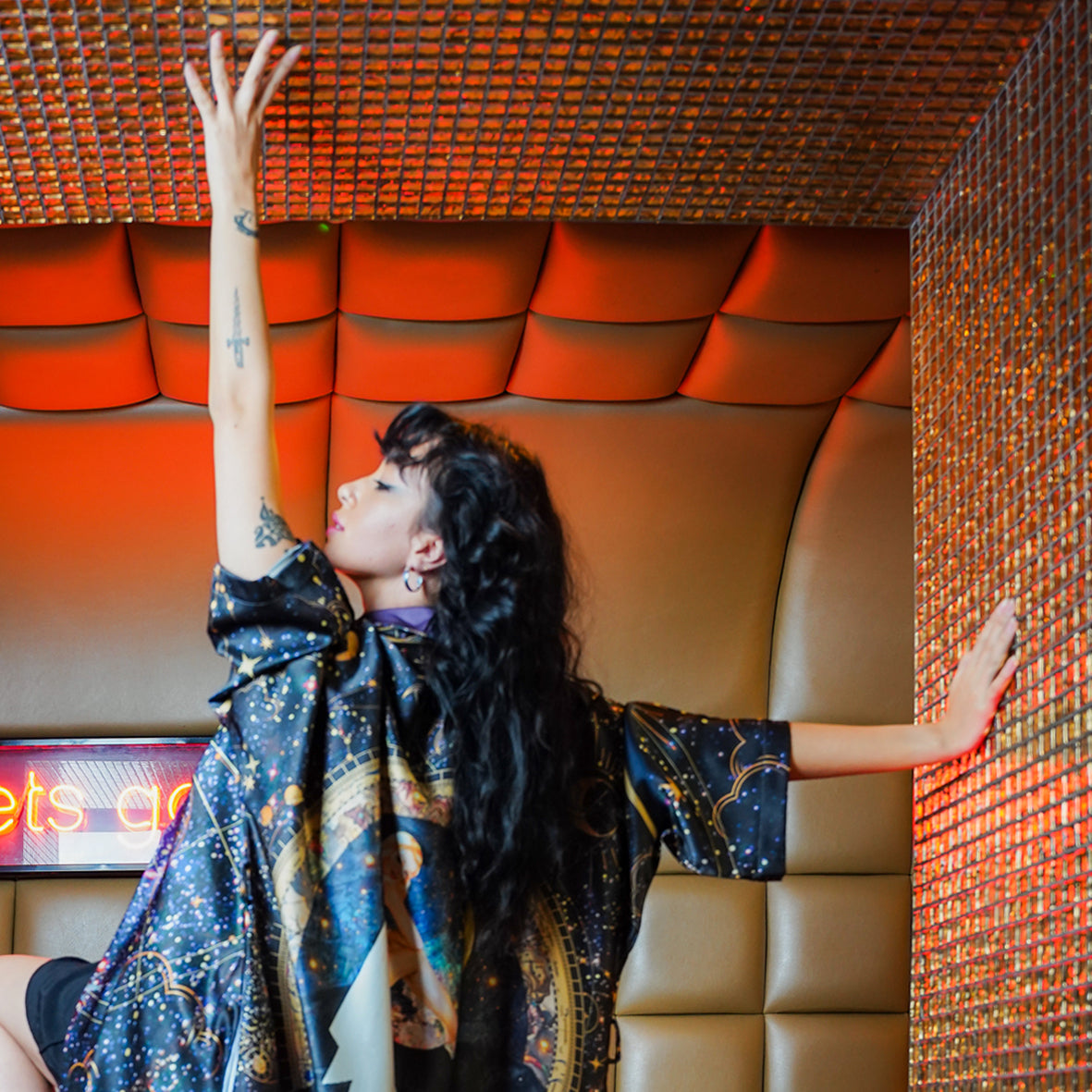 A female model wearing a Luxury 100% silk kimono in a maximalist celestial design called - Celeste dancing in a nightclub setting 