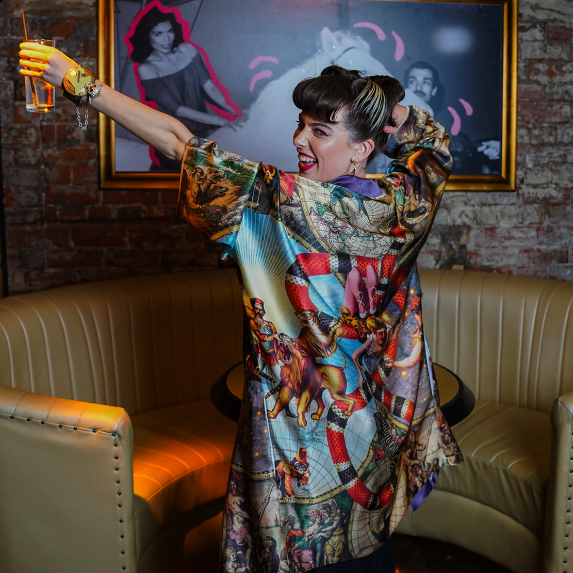 A female model in a bar showing the back view of luxury 100% silk kimono in a maximalist Vintage Circus design