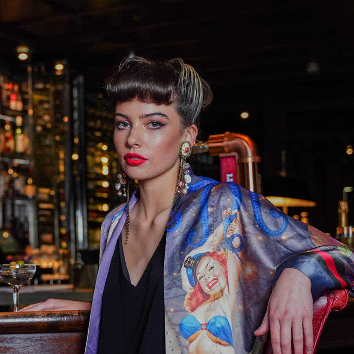 Female model in a bar wearing luxury 100% silk kimono in a maximalist retro pinup design