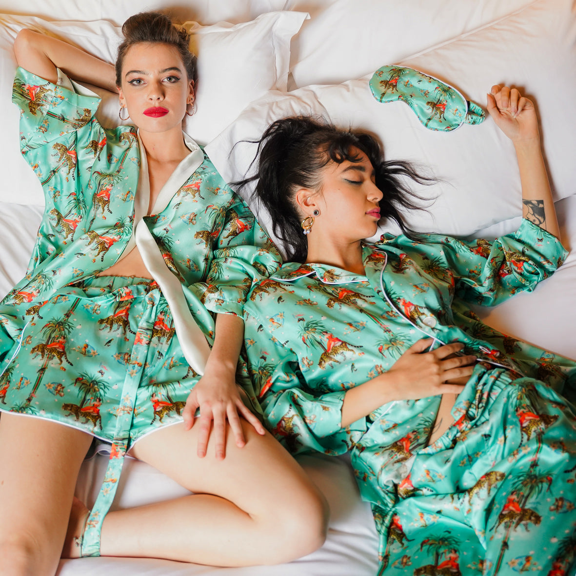 Two models laying on a bed wearing luxury 100% silk kimono and Pyjama Set in a maximalist retro pinup design