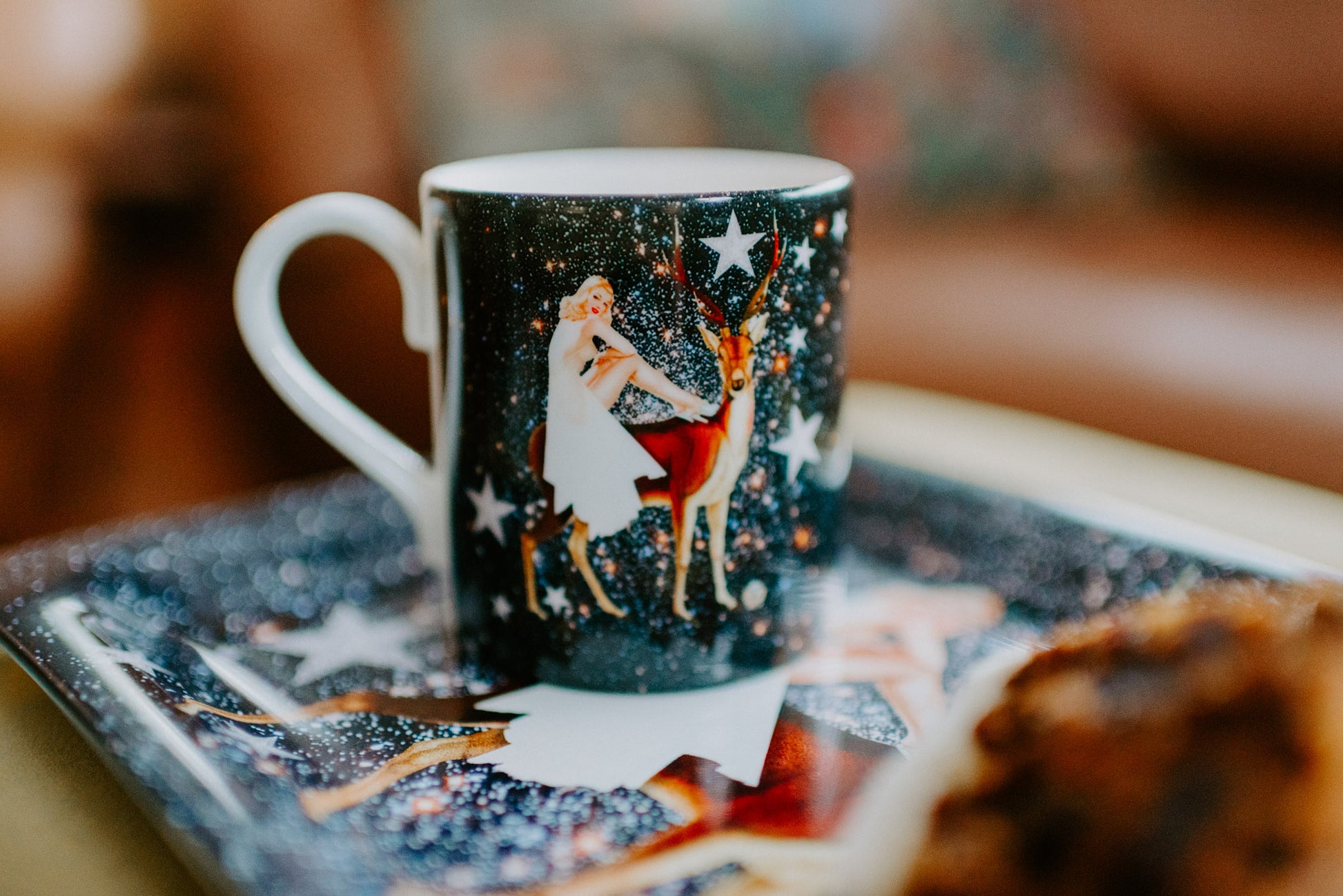 Luxury bone china coffee cup in a maximalist festive astrology design called - festive celeste placed on a tray with cake