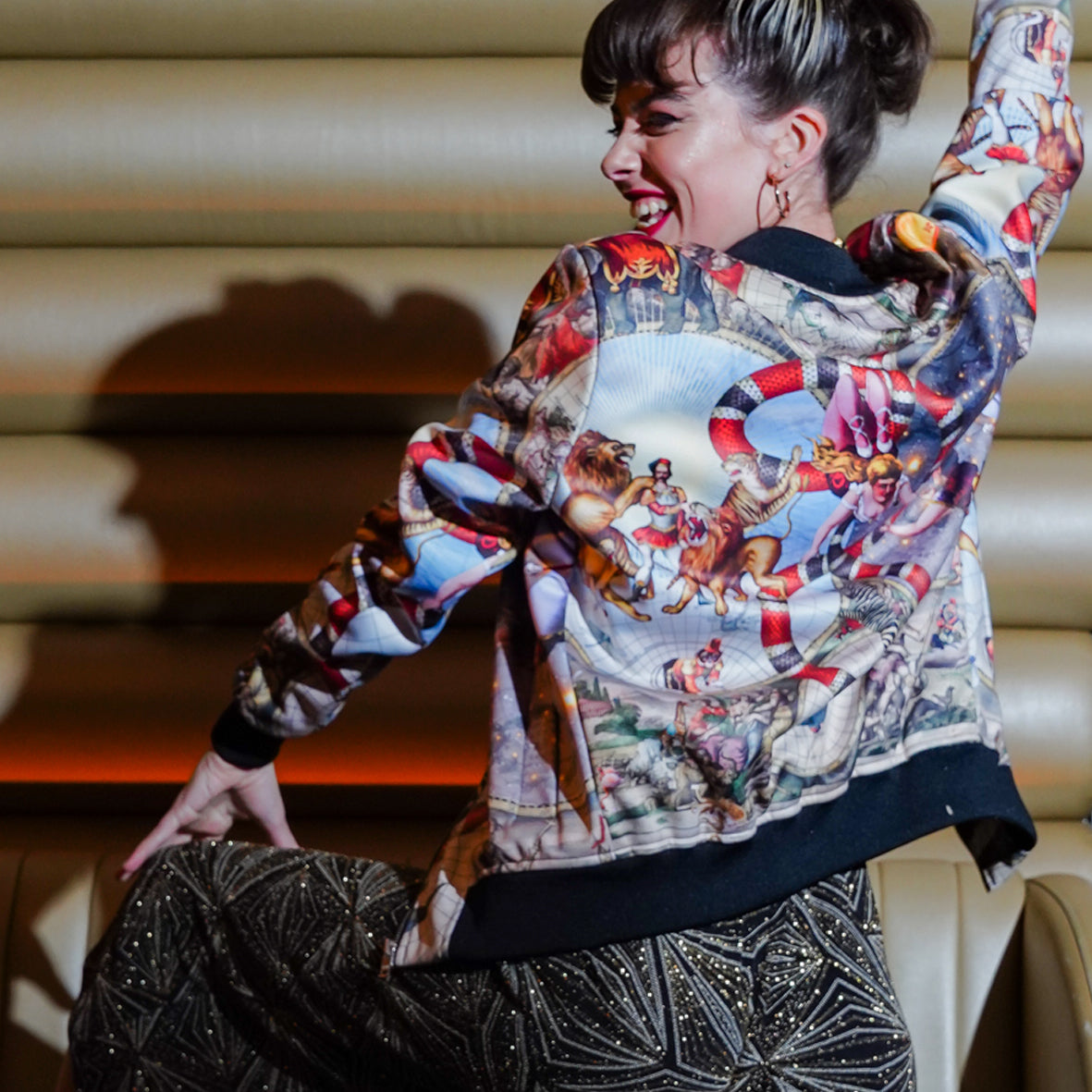 A female model showing the back view of luxury softshell bomber jacket in a maximalist Circus inspired design